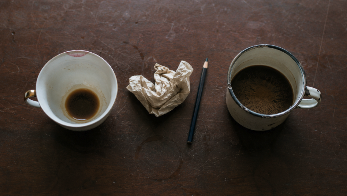 Coffee cups, crumpled paper, and pencil on table symbolising unclear procurement savings claims and financial scrutiny in Melbourne